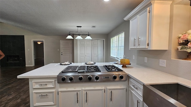 2402 Heather St, Highlands, TX 77562 - kitchen featuring stainless steel gas stovetop, dark wood-type flooring, white cabinets, a peninsula, and pendant lighting