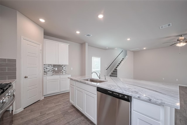 24711 Sonora Crescent Cir, Huffman, TX 77336 - kitchen featuring stainless steel appliances, a ceiling fan, tasteful backsplash, light wood-style floors, and light stone counters