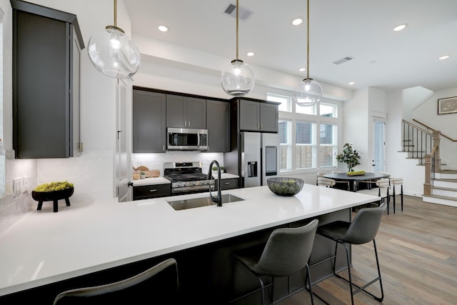 9315A Montridge Dr, Houston, TX 77080 - kitchen featuring appliances with stainless steel finishes, a peninsula, light wood finished floors, backsplash, and a breakfast bar