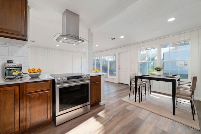 800 E Adoue St, Baytown, TX 77520 - kitchen with stainless steel electric range, island exhaust hood, wood finished floors, light countertops, and brown cabinetry