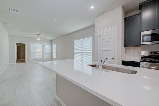 218 Emerald Thicket Ln, Huffman, TX 77336 - kitchen featuring stainless steel appliances, light countertops, a ceiling fan, backsplash, and dark cabinets