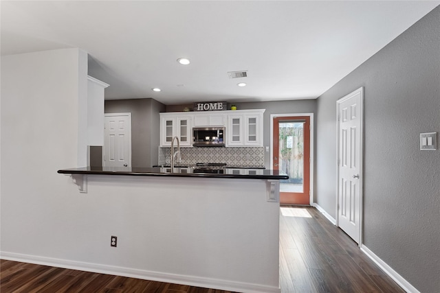 2623 Woodridge Cove Dr, Houston, TX 77087 - kitchen with stainless steel microwave, white cabinets, dark wood-type flooring, dark countertops, and recessed lighting