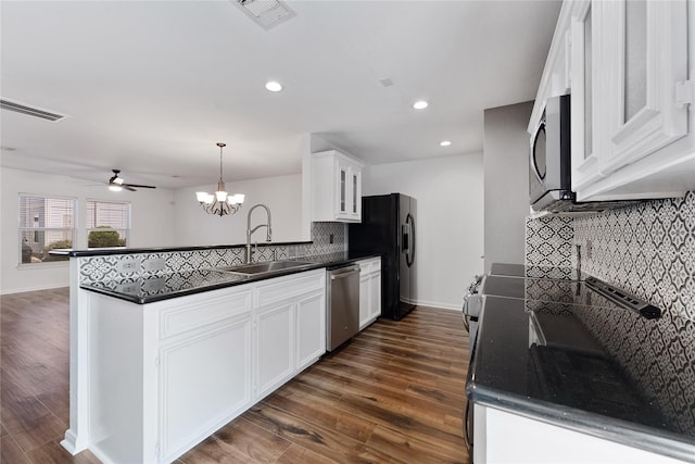 2623 Woodridge Cove Dr, Houston, TX 77087 - kitchen with appliances with stainless steel finishes, dark countertops, a peninsula, backsplash, and white cabinetry