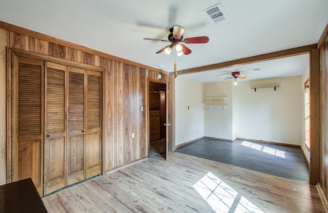 810 Roosevelt St, Sealy, TX 77474 - unfurnished bedroom with wooden walls, light wood-style floors, and a ceiling fan