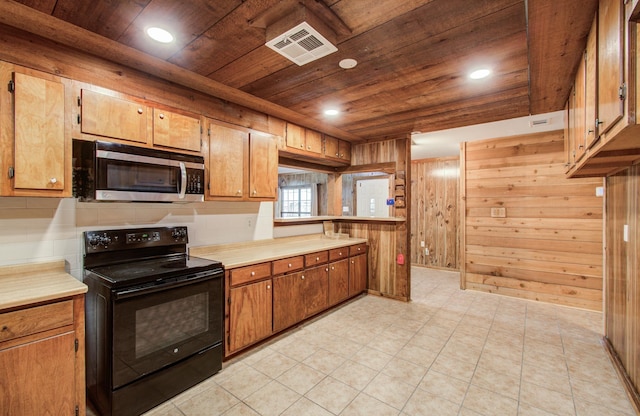 810 Roosevelt St, Sealy, TX 77474 - kitchen with black electric range, stainless steel microwave, wood ceiling, wood walls, and light countertops