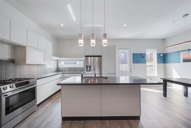 5509 Paraiso Pl, Houston, TX 77091 - kitchen featuring stainless steel appliances, modern cabinets, white cabinets, a kitchen island with sink, and decorative backsplash