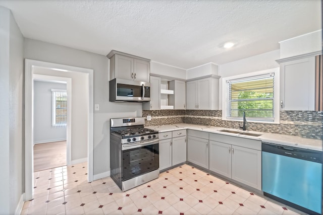 4517 W 43rd St, Houston, TX 77092 - kitchen with appliances with stainless steel finishes, gray cabinets, plenty of natural light, decorative backsplash, and a textured ceiling