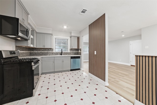 4517 W 43rd St, Houston, TX 77092 - kitchen featuring stainless steel appliances, gray cabinetry, decorative backsplash, light floors, and recessed lighting