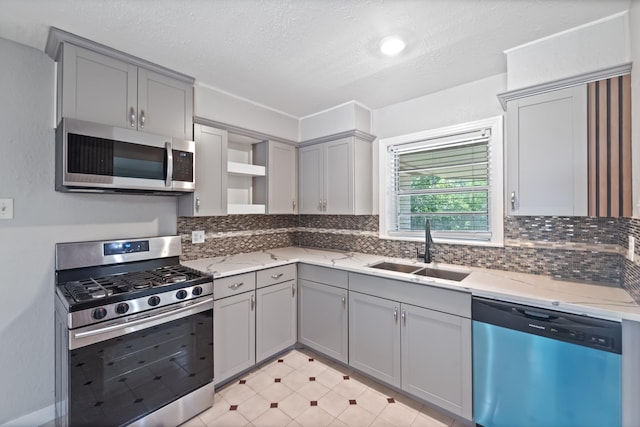 4517 W 43rd St, Houston, TX 77092 - kitchen with appliances with stainless steel finishes, gray cabinetry, open shelves, a textured ceiling, and decorative backsplash