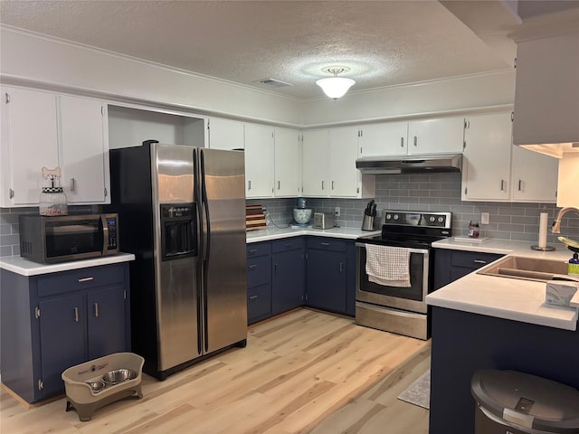 813 Camelot Ln, Friendswood, TX 77546 - kitchen with appliances with stainless steel finishes, under cabinet range hood, a textured ceiling, light wood-style flooring, and tasteful backsplash
