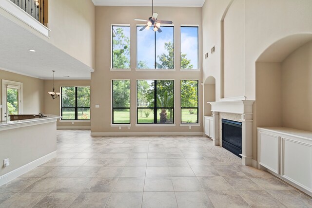 52 Tall Trl, Missouri City, TX 77459 - unfurnished living room with ceiling fan, a towering ceiling, a glass covered fireplace, a chandelier, and crown molding