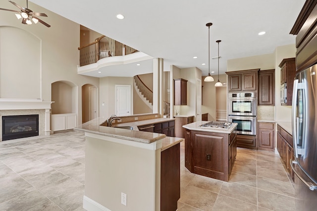 52 Tall Trl, Missouri City, TX 77459 - kitchen with a center island, appliances with stainless steel finishes, ceiling fan, open floor plan, and a glass covered fireplace