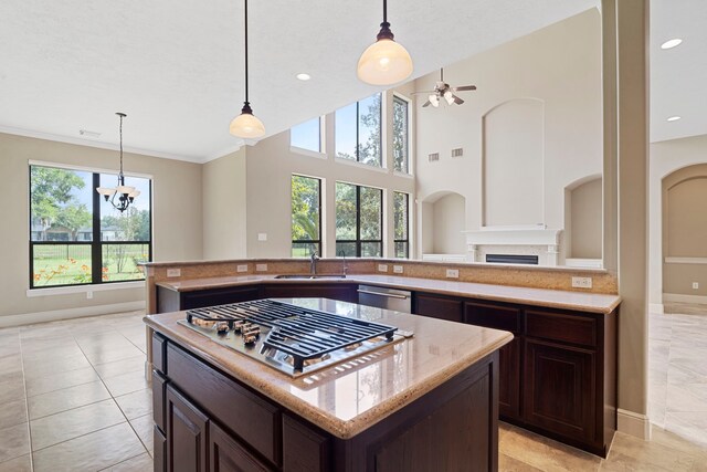 52 Tall Trl, Missouri City, TX 77459 - kitchen featuring stainless steel appliances, a fireplace, a ceiling fan, dark brown cabinetry, and light stone countertops
