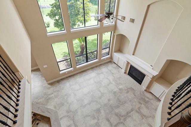 52 Tall Trl, Missouri City, TX 77459 - unfurnished living room featuring a towering ceiling, ceiling fan, healthy amount of natural light, and a glass covered fireplace