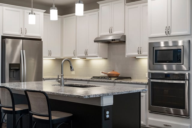 10118 Cypress Path, Missouri City, TX 77459 - kitchen with appliances with stainless steel finishes, under cabinet range hood, tasteful backsplash, a kitchen island with sink, and a kitchen bar
