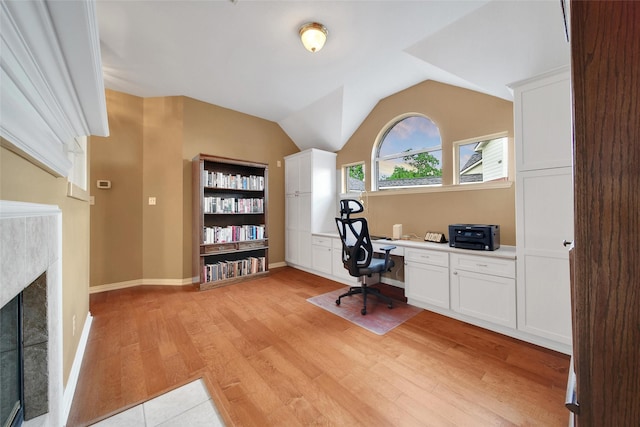 22710 Sierra Lake Ct, Katy, TX 77494 - home office featuring built in desk, light wood-style floors, a tiled fireplace, and lofted ceiling