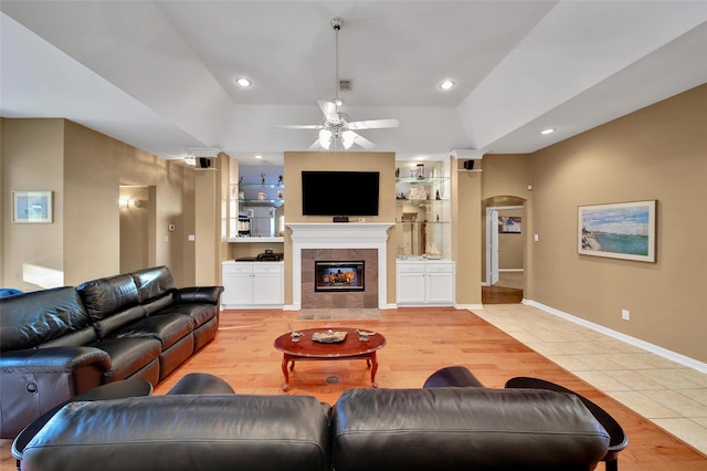 22710 Sierra Lake Ct, Katy, TX 77494 - living area with arched walkways, light tile patterned floors, a ceiling fan, a tile fireplace, and built in features