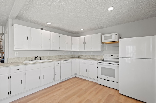 4034 Reeves Dr, Galveston, TX 77554 - kitchen with white appliances, a textured ceiling, light wood-style flooring, white cabinets, and light countertops