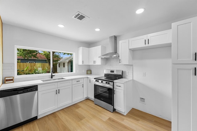 3303 Dartmouth Dr, Pasadena, TX 77503 - kitchen featuring stainless steel appliances, wall chimney range hood, light wood-style floors, light countertops, and tasteful backsplash