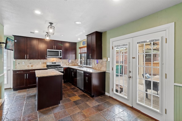 2802 Sandpebble Dr, Seabrook, TX 77586 - kitchen with appliances with stainless steel finishes, french doors, stone tile floors, a kitchen island, and recessed lighting