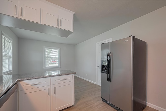 2401 33rd Ave N, Texas City, TX 77590 - kitchen featuring stainless steel appliances, white cabinetry, light wood-style floors, light stone counters, and a peninsula
