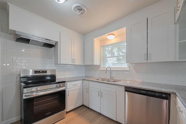2401 33rd Ave N, Texas City, TX 77590 - kitchen with appliances with stainless steel finishes, extractor fan, white cabinetry, and light stone countertops