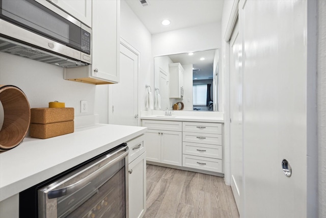 1050 Timbergrove Yards Ln, Houston, TX 77008 - kitchen with stainless steel microwave, white cabinets, light countertops, light wood-style flooring, and recessed lighting