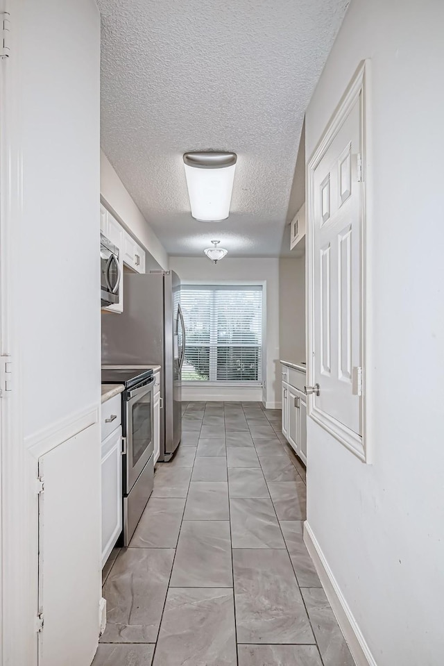 8427 Ariel St, Houston, TX 77074 - kitchen with appliances with stainless steel finishes, white cabinets, a textured ceiling, light marble finish floors, and light countertops
