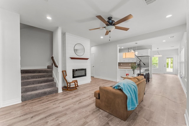 719 Cherokee Dr, Conroe, TX 77316 - living room with a ceiling fan, light wood-type flooring, a large fireplace, recessed lighting, and stairs