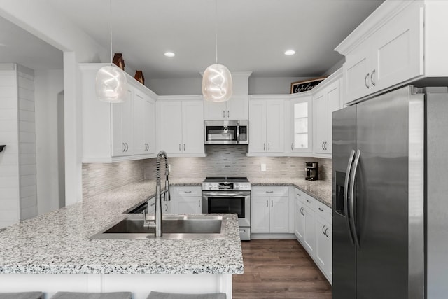 719 Cherokee Dr, Conroe, TX 77316 - kitchen with appliances with stainless steel finishes, a peninsula, white cabinets, backsplash, and recessed lighting