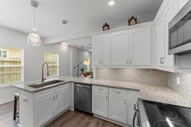 719 Cherokee Dr, Conroe, TX 77316 - kitchen featuring appliances with stainless steel finishes, dark wood finished floors, white cabinets, a peninsula, and decorative backsplash