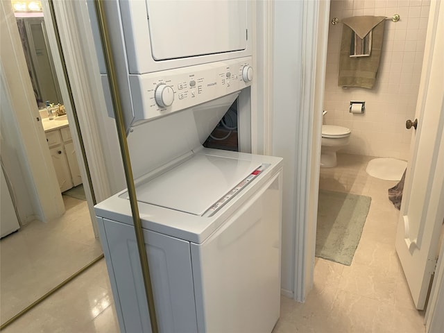 5050 Ambassador Way Unit 201, Houston, TX 77056 - laundry area featuring stacked washer / drying machine, tile walls, and light tile patterned flooring