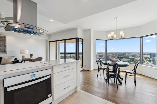 2001 Holcombe Blvd Unit 2305, Houston, TX 77030 - kitchen with oven, island exhaust hood, a chandelier, white cabinets, and decorative light fixtures