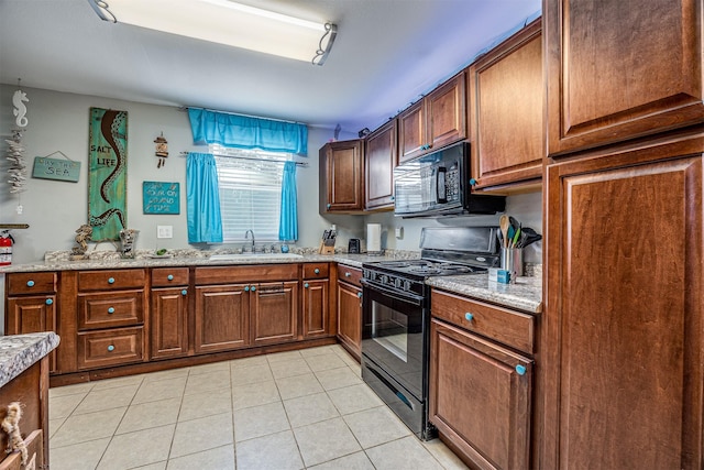 1315 40th St, Rear, Galveston, TX 77550 - kitchen with black appliances, light tile patterned floors, light stone counters, and brown cabinetry