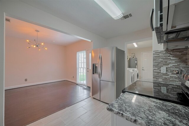 3930 Daphne St, Houston, TX 77021 - kitchen with stainless steel fridge, washer and clothes dryer, decorative backsplash, a chandelier, and electric water heater