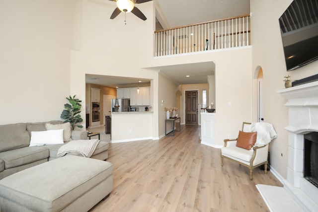 15802 Aberdeen Trails Dr, Houston, TX 77095 - living area with a fireplace with raised hearth, ceiling fan, a high ceiling, light wood-style floors, and arched walkways