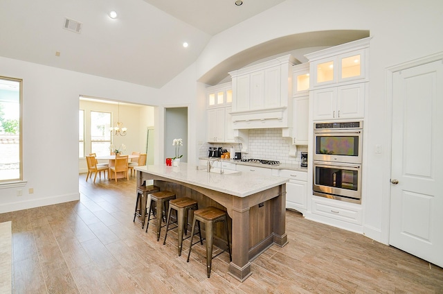 27522 Blackstone Canyon Ln, Katy, TX 77494 - kitchen with appliances with stainless steel finishes, lofted ceiling, backsplash, a chandelier, and a kitchen breakfast bar