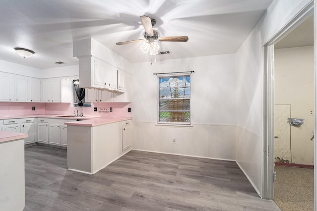 14030 Duncannon Dr, Houston, TX 77015 - kitchen with white cabinets, a ceiling fan, a peninsula, light countertops, and wood finished floors