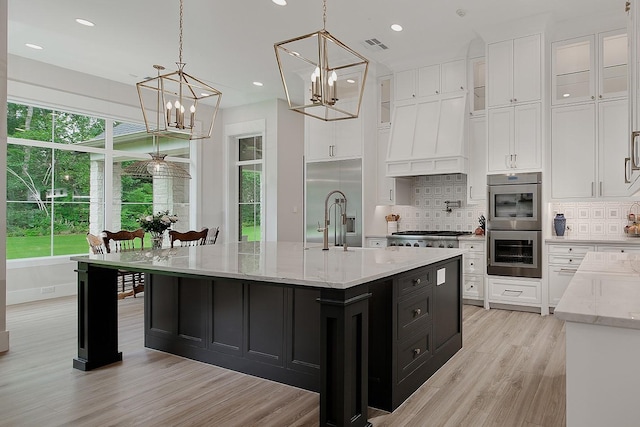 27003 Hidden Grove Landing Dr, Spring, TX 77386 - kitchen featuring dark cabinets, white cabinets, decorative backsplash, a chandelier, and light wood-type flooring