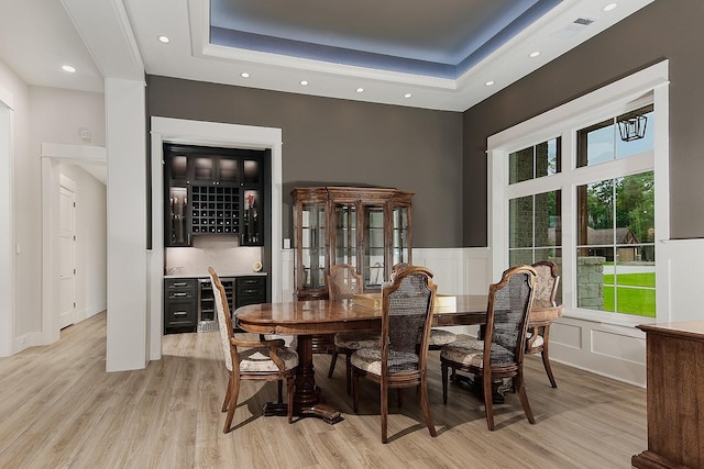 27003 Hidden Grove Landing Dr, Spring, TX 77386 - dining space with wine cooler, a dry bar, light wood finished floors, a tray ceiling, and a wainscoted wall