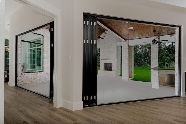 27003 Hidden Grove Landing Dr, Spring, TX 77386 - doorway to outside with an outdoor fireplace, ceiling fan, wood finished floors, wood ceiling, and brick wall