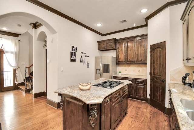1241 W 24th St Unit B, Houston, TX 77008 - kitchen featuring stainless steel appliances, arched walkways, ornamental molding, tasteful backsplash, and light wood-style floors