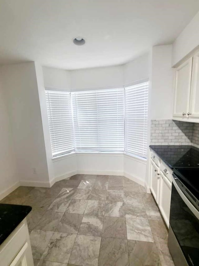 7447 Cambridge St Unit 8, Houston, TX 77054 - kitchen featuring stainless steel range with electric cooktop, dark countertops, backsplash, and white cabinets