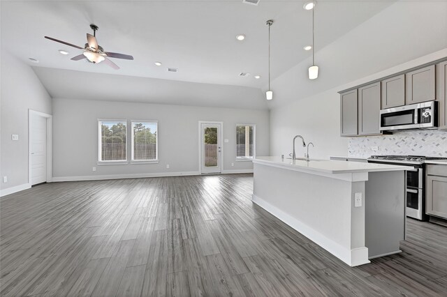 10329 S Goshawk Trl, Conroe, TX 77385 - kitchen featuring appliances with stainless steel finishes, gray cabinets, a center island with sink, backsplash, and open floor plan