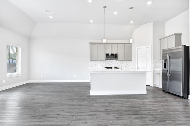 10329 S Goshawk Trl, Conroe, TX 77385 - kitchen with stainless steel appliances, gray cabinets, lofted ceiling, an island with sink, and decorative backsplash