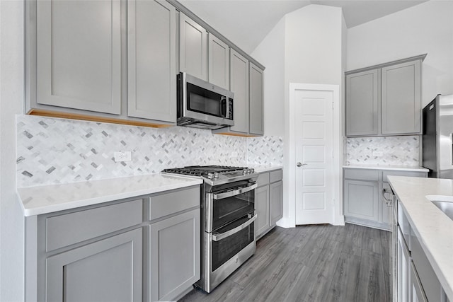 10329 S Goshawk Trl, Conroe, TX 77385 - kitchen with appliances with stainless steel finishes, gray cabinets, decorative backsplash, dark wood-type flooring, and vaulted ceiling