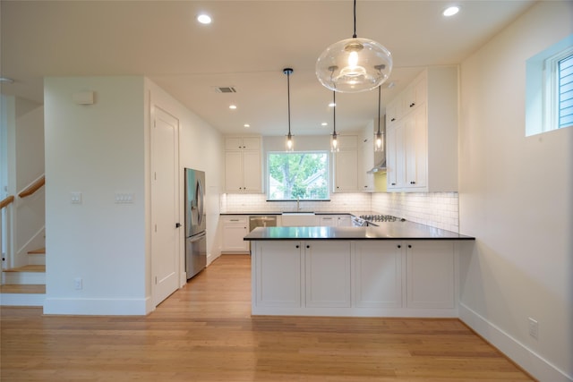1037 Rutland St, Houston, TX 77008 - kitchen featuring white cabinets, a peninsula, stainless steel appliances, tasteful backsplash, and light wood-style flooring