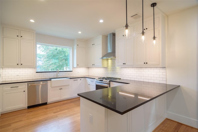 1037 Rutland St, Houston, TX 77008 - kitchen featuring appliances with stainless steel finishes, wall chimney range hood, light wood-style flooring, white cabinetry, and recessed lighting