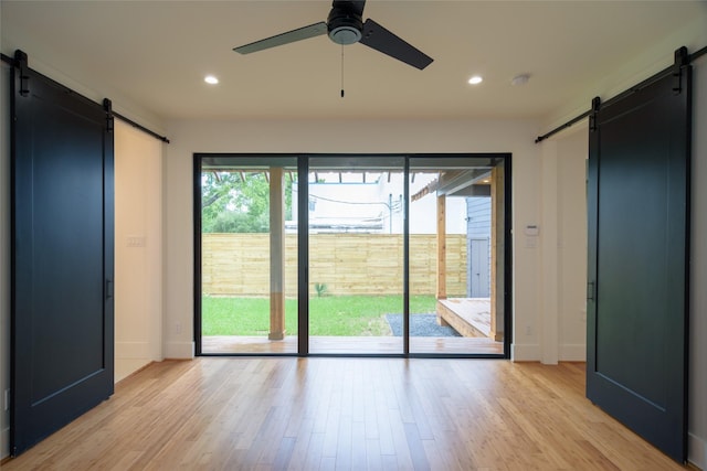 1037 Rutland St, Houston, TX 77008 - unfurnished bedroom with a barn door, access to outside, light wood-type flooring, and recessed lighting
