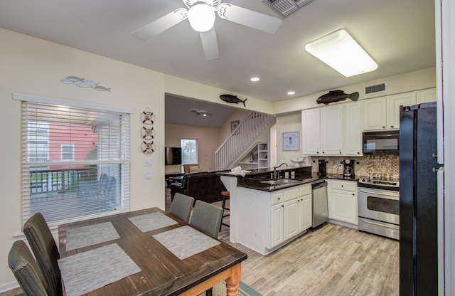 16713 Kingston Way, Jamaica Beach, TX 77554 - kitchen featuring black appliances, a ceiling fan, a peninsula, dark countertops, and white cabinets